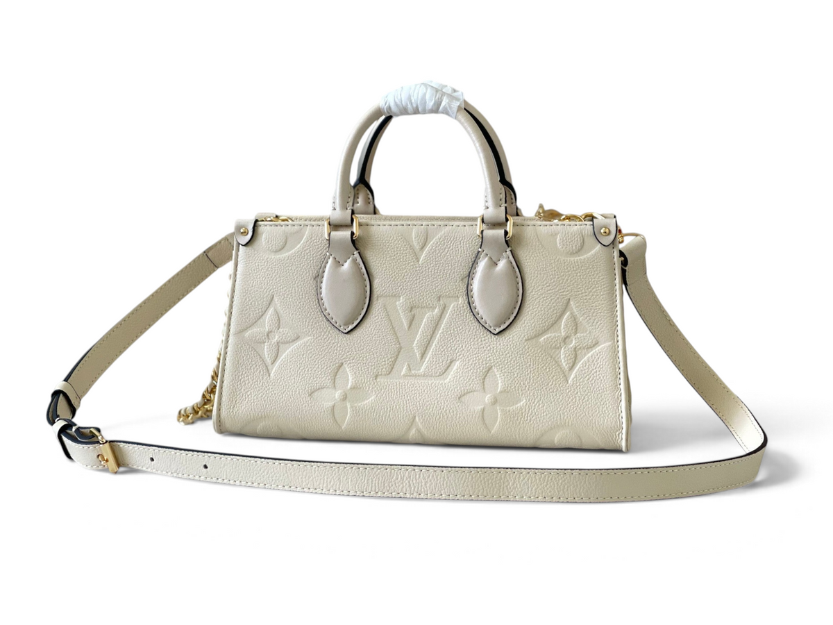 SWORD LUXURY imzalı, krem rengi Monogram Empreinte deri Louis Vuitton OnTheGo East West çanta, altın zincir detaylı.