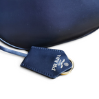 SWORD LUXURY Prada mini deri omuz çantası, altın tonlu logo detaylı deri etiket ve pürüzsüz lacivert deri yüzey.