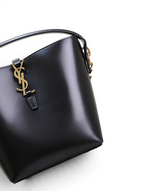 SWORD LUXURY siyah kutu dana derisi Le 37 kova çanta, altın tonlu YSL monogram detaylı ve yapılandırılmış tasarım.