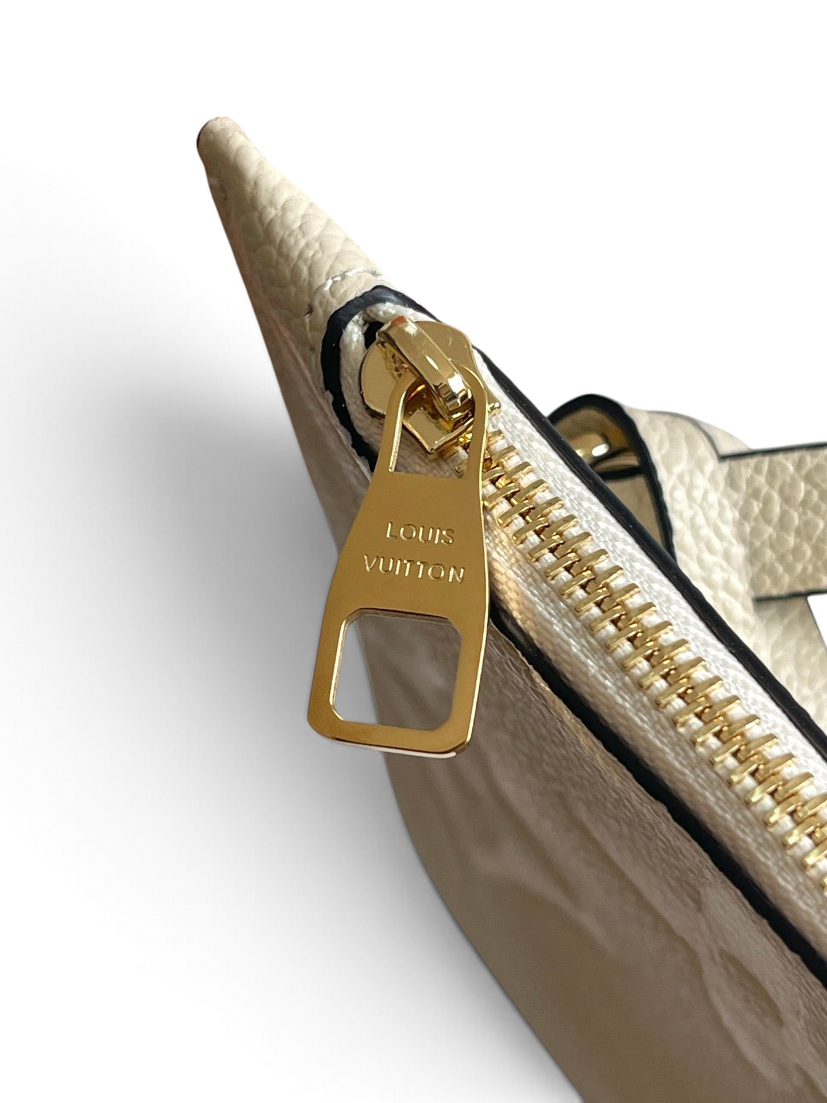 SWORD LUXURY krem rengi kanvas çanta üzerinde altın tonlu metal fermuar detayı ve Louis Vuitton marka logosu.