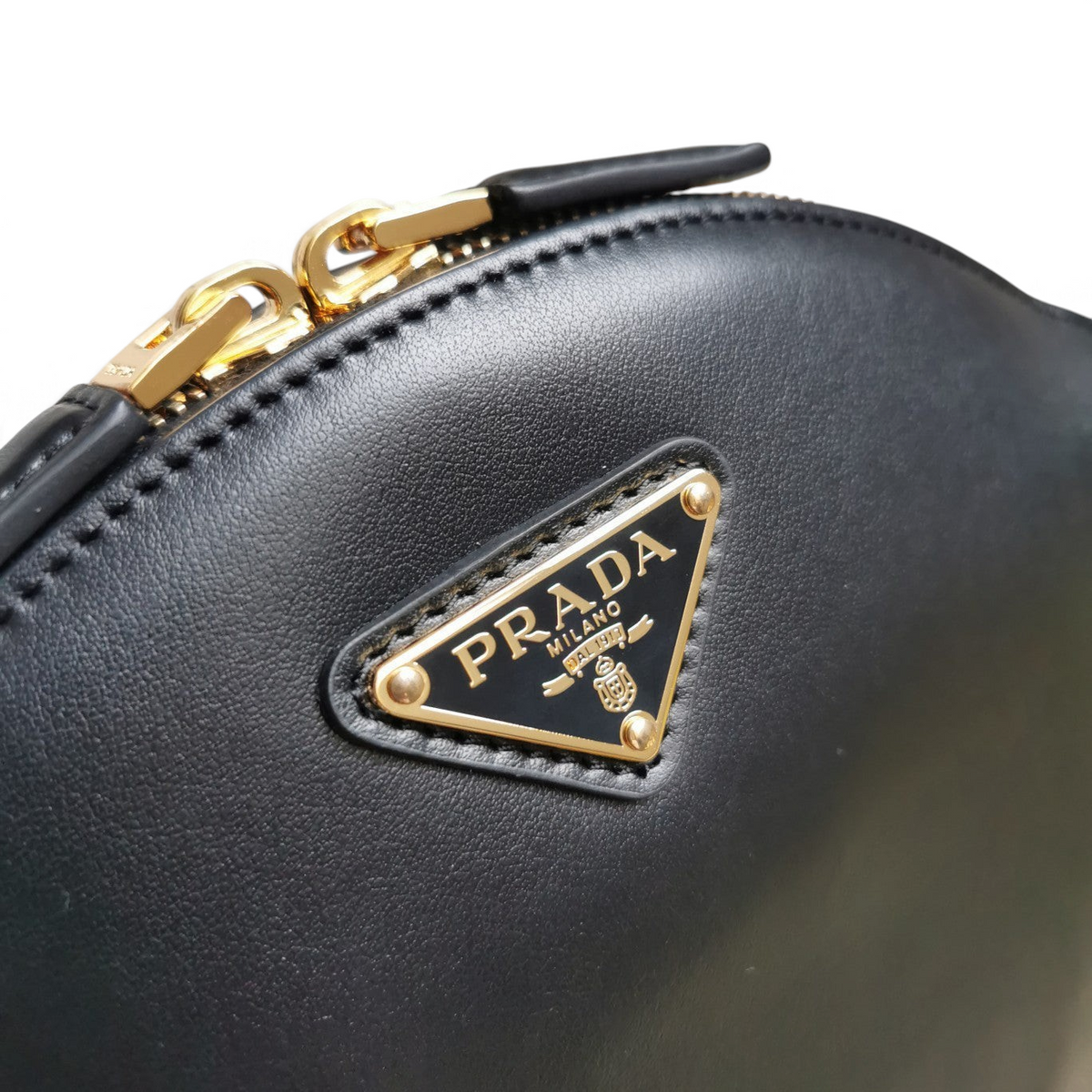 SWORD LUXURY Prada siyah deri mini omuz çantası, altın tonlu metal logo ve fermuar detaylı yakın çekim.