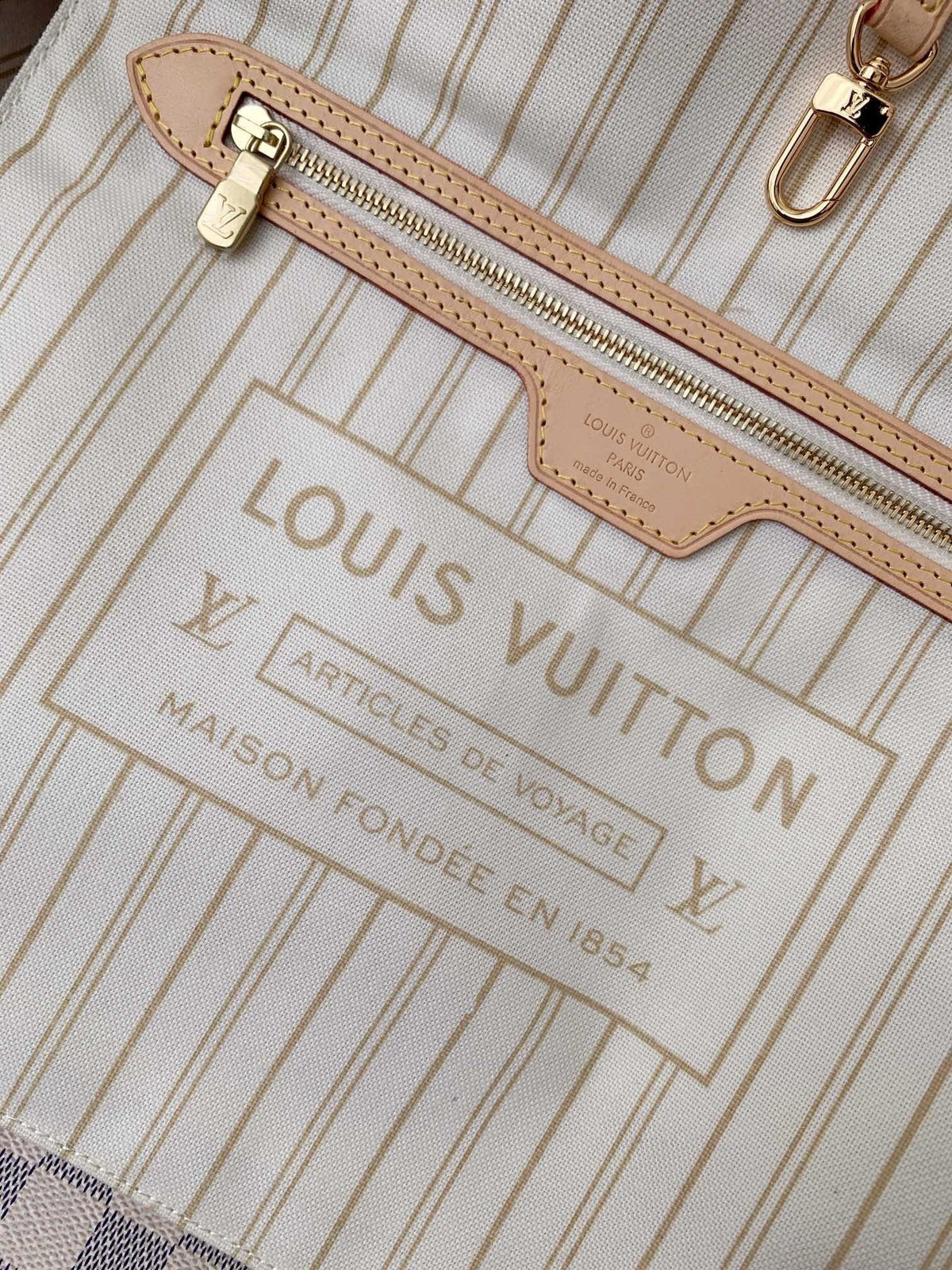 SWORD LUXURY Neverfull MM çanta iç detayı, bej çizgili astar, deri fermuarlı cep ve altın rengi metal aksesuarlar.