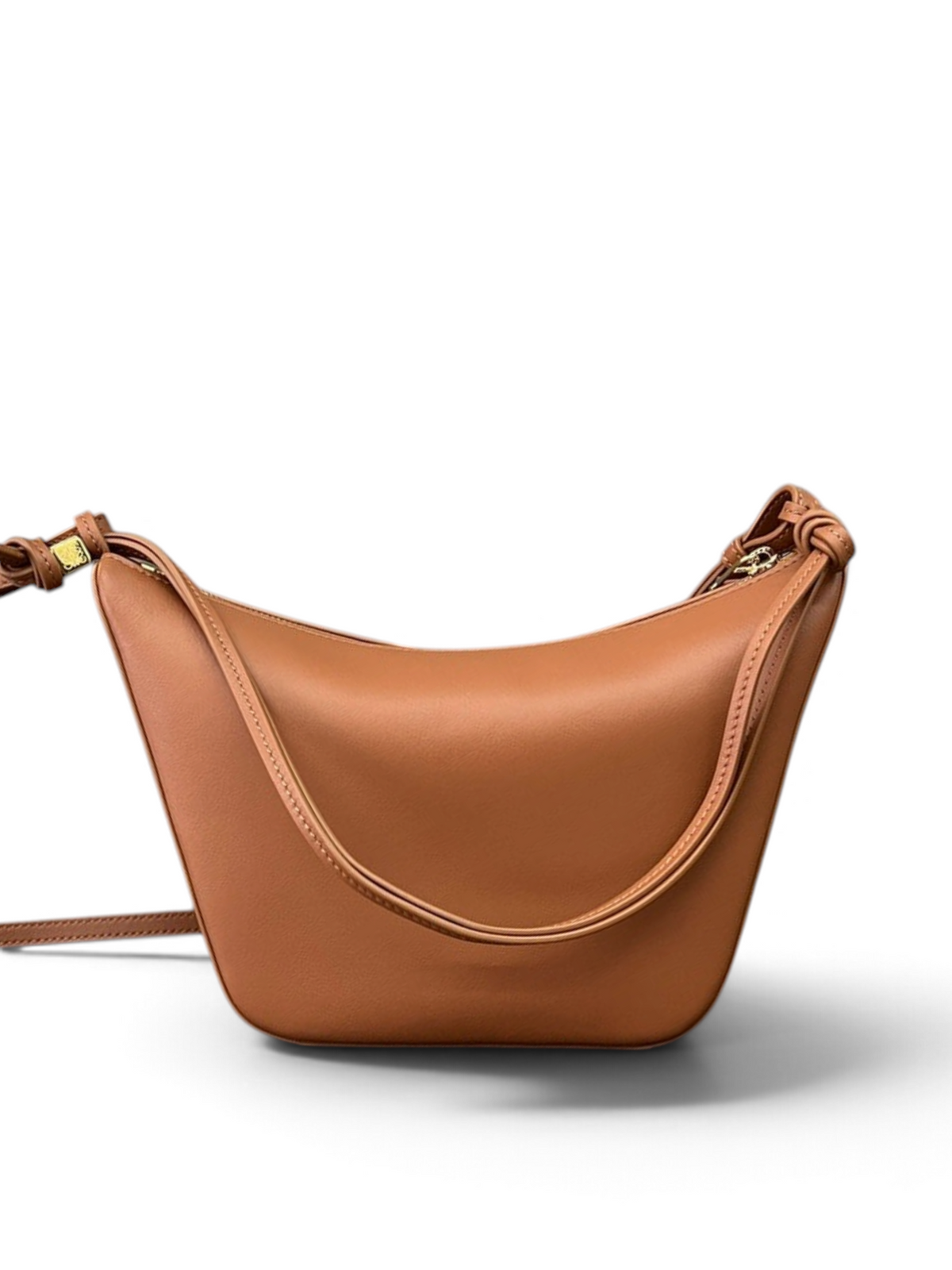 Brown leather handbag on a wooden surface with a book and decorative items in the background