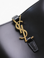 SWORD LUXURY siyah kutu dana derisi çanta üzerinde fırçalanmış altın tonlu ikonik YSL monogram detayı