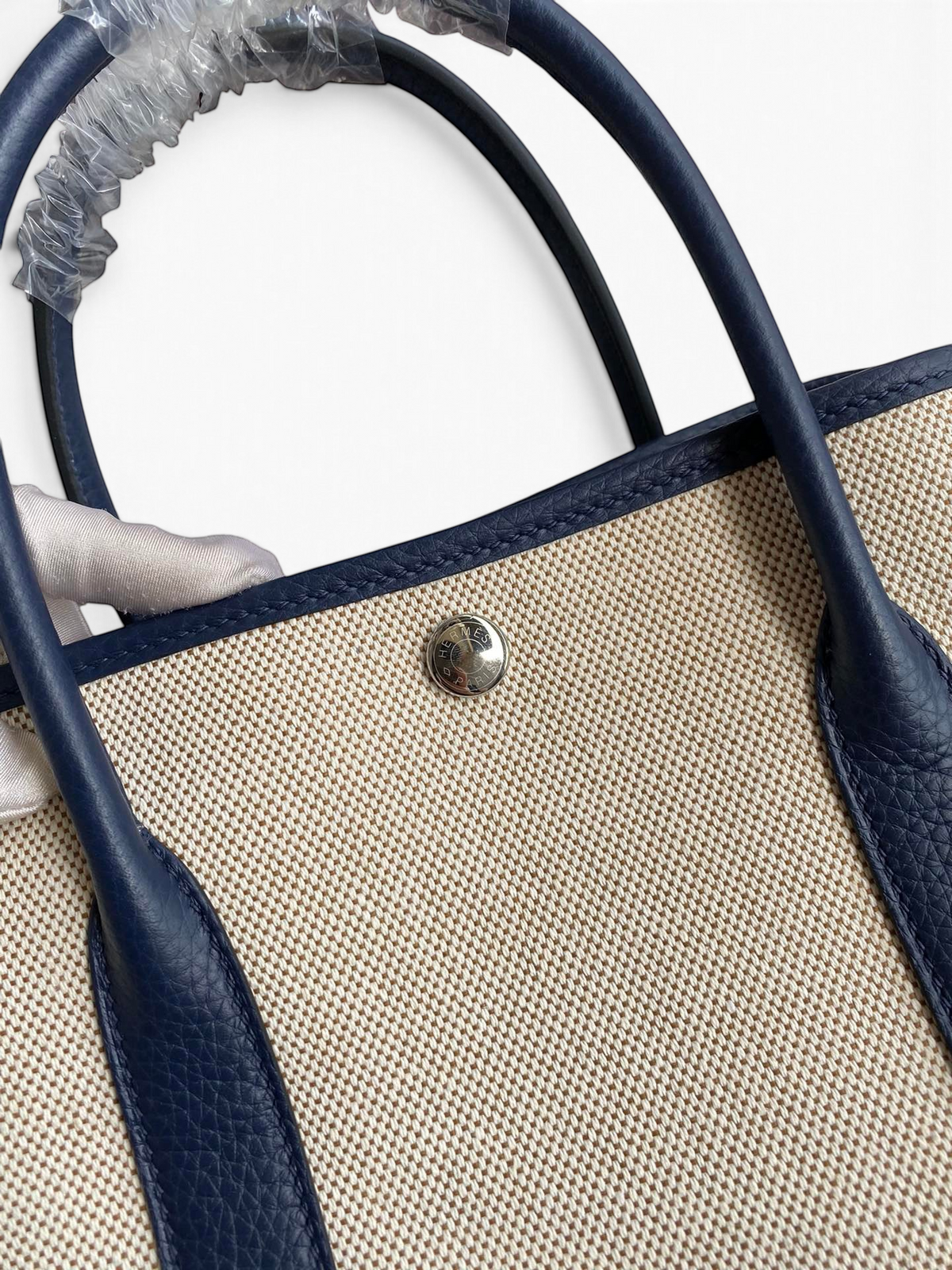 SWORD LUXURY Hermès Garden Party 30 çanta, bej kanvas ve lacivert deri detaylı, metal çıtçıtlı üst kapama.