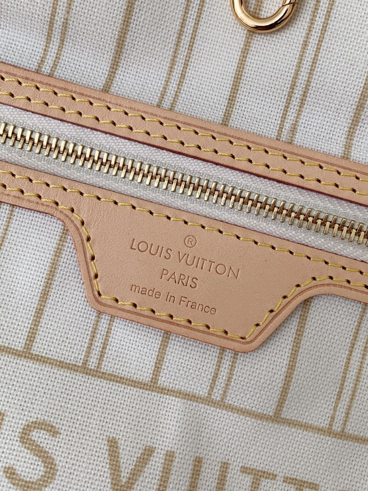 SWORD LUXURY Neverfull MM çanta iç detayında deri etiket, fermuarlı cep ve krem rengi çizgili astar görünümü.