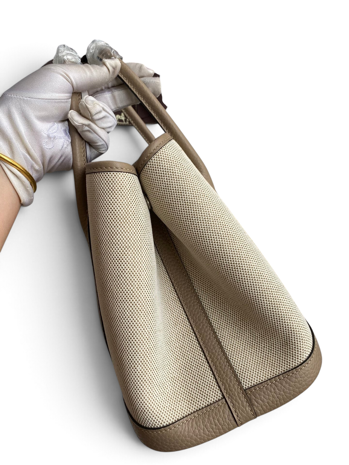 SWORD LUXURY marka bej kanvas ve deri detaylı Hermès Garden Party 30 çanta, kutusunda tutulurken yan görünüm.