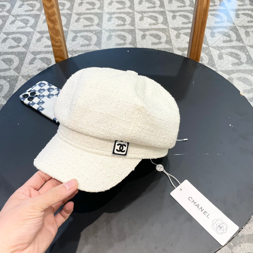 White Chanel cap on a black surface with a visible tag, on a patterned floor background.