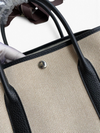 SWORD LUXURY Hermès Garden Party 30 çanta, bej kanvas ve siyah deri detaylı, gümüş çıtçıtlı tasarım.