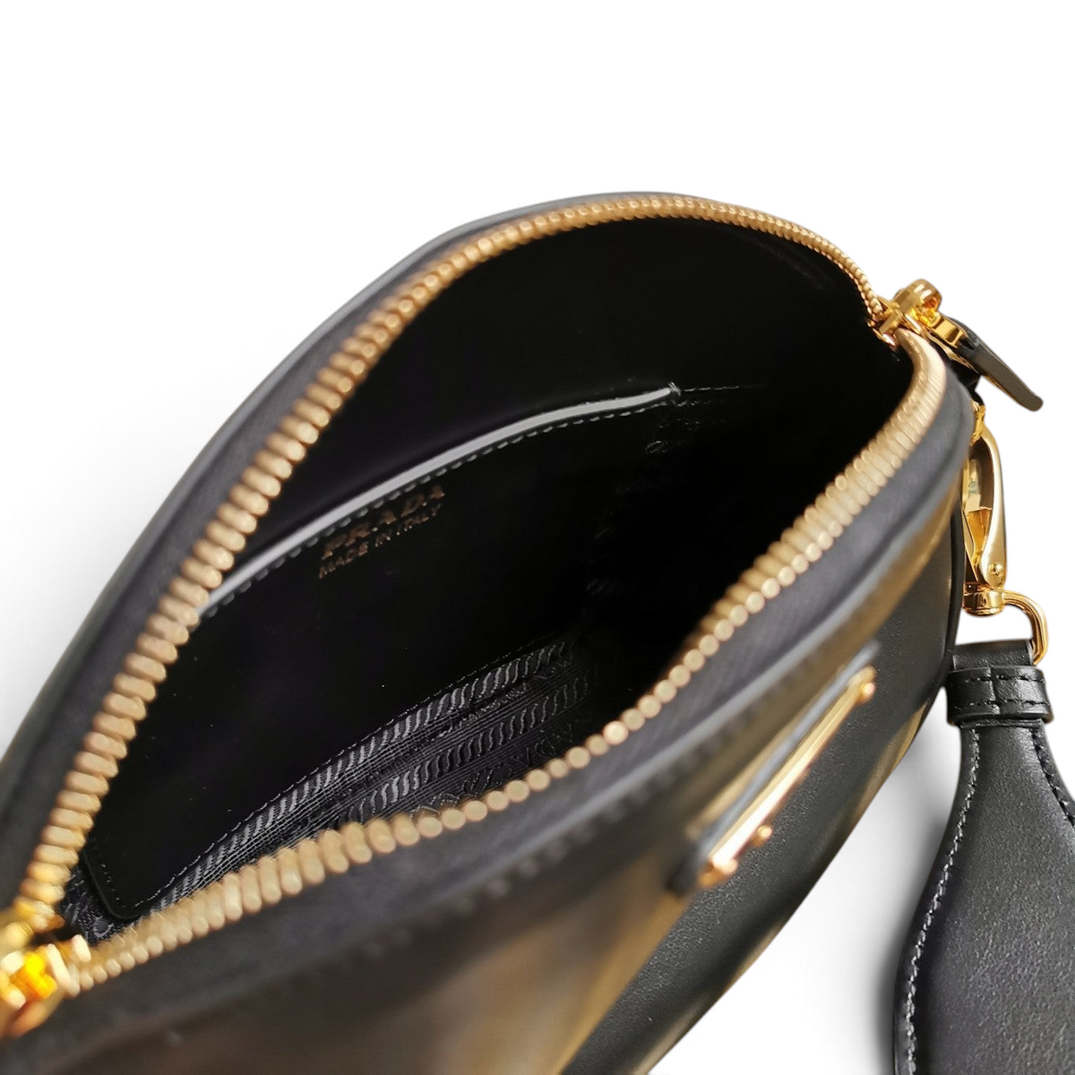 SWORD LUXURY Prada mini siyah deri omuz çantasının altın tonlu fermuarlı ve geniş iç bölmeli detaylı görünümü.