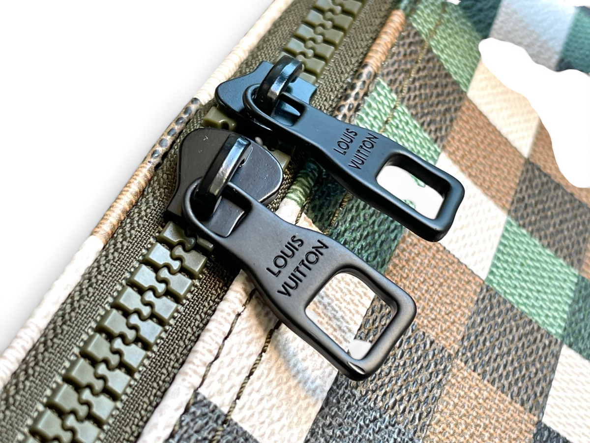 SWORD LUXURY Louis Vuitton Keepall Bandoulière 50 çanta üzerinde mat yeşil metal fermuar detayları ve piksel kamuflaj desenli kanvas.