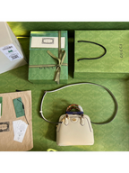 SWORD LUXURY Gucci Diana deri çanta, bambu saplı, mor detaylı, kutu ve aksesuarlarıyla birlikte yeşil zeminde.