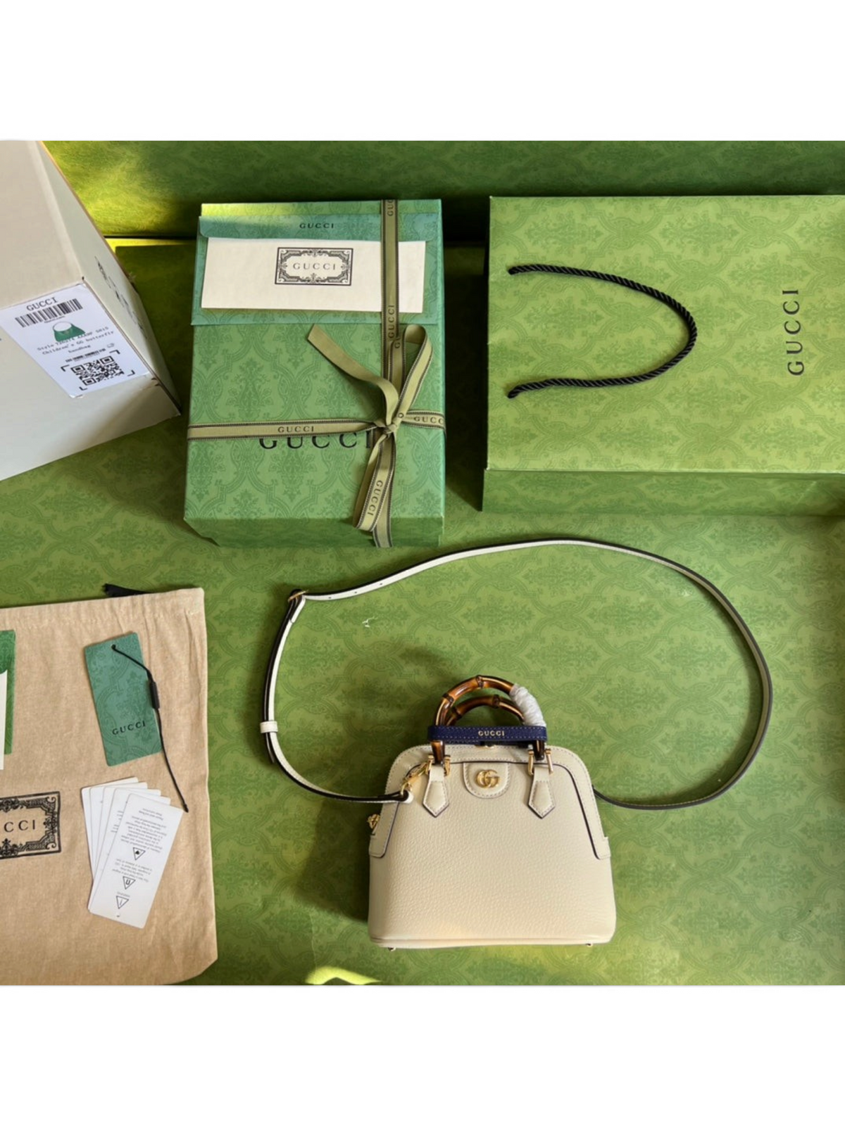 SWORD LUXURY Gucci Diana deri çanta, bambu saplı, mor detaylı, kutu ve aksesuarlarıyla birlikte yeşil zeminde.