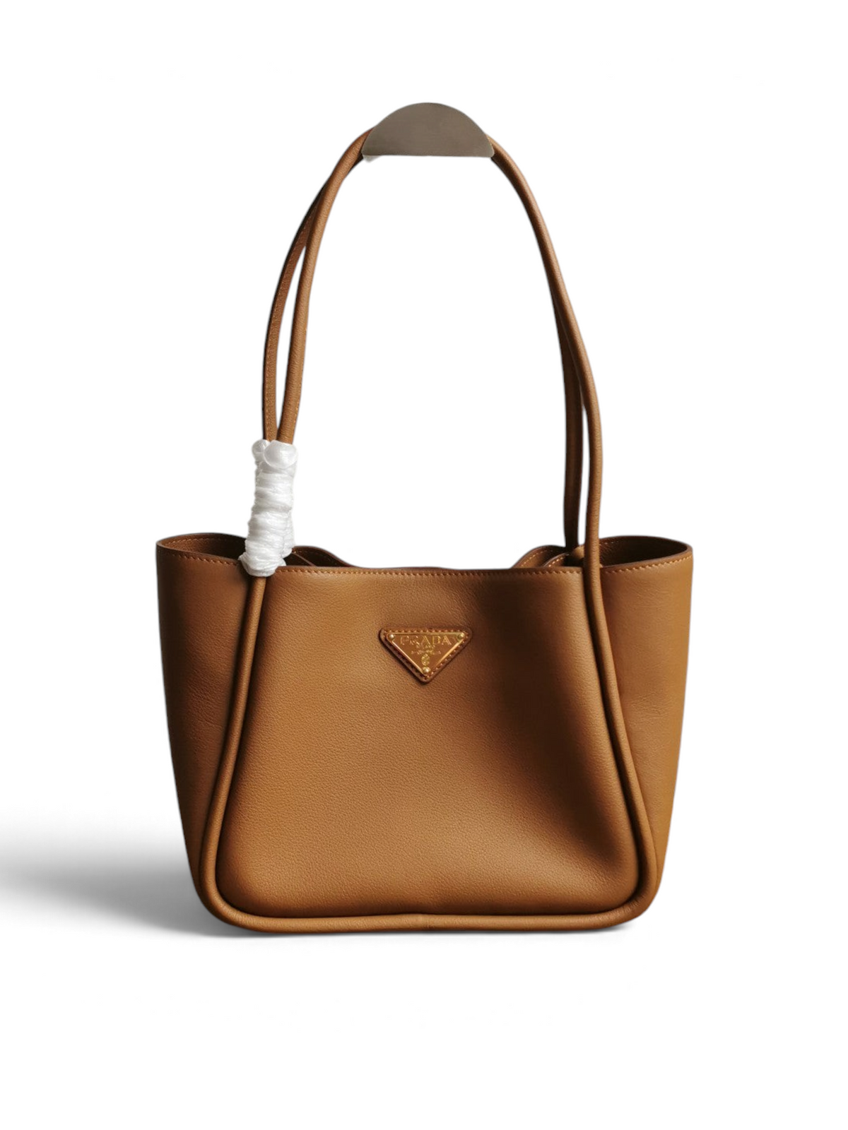SWORD LUXURY marka, altın tonlu logo detaylı, taba rengi yumuşak dokulu deri Prada tote çanta.