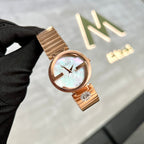 Rose gold Gucci watch held by a gloved hand with a blurred background