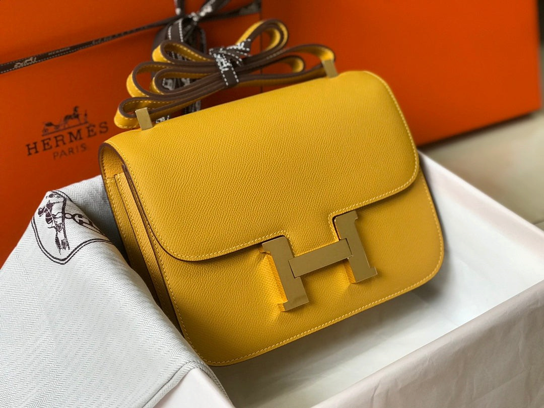 SWORD LUXURY imzalı, altın donanımlı ve ikonik H tokalı, canlı sarı Epsom deri Hermès Constance 18 çanta.