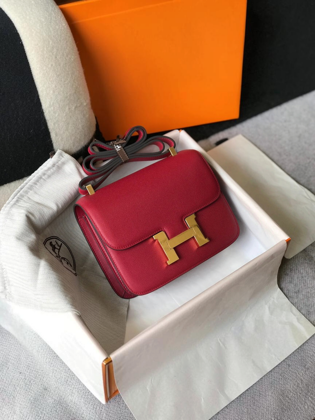 SWORD LUXURY marka, altın H tokalı, derin kırmızı deri Hermès Constance 18 çanta, kutusu ve toz torbası içinde.