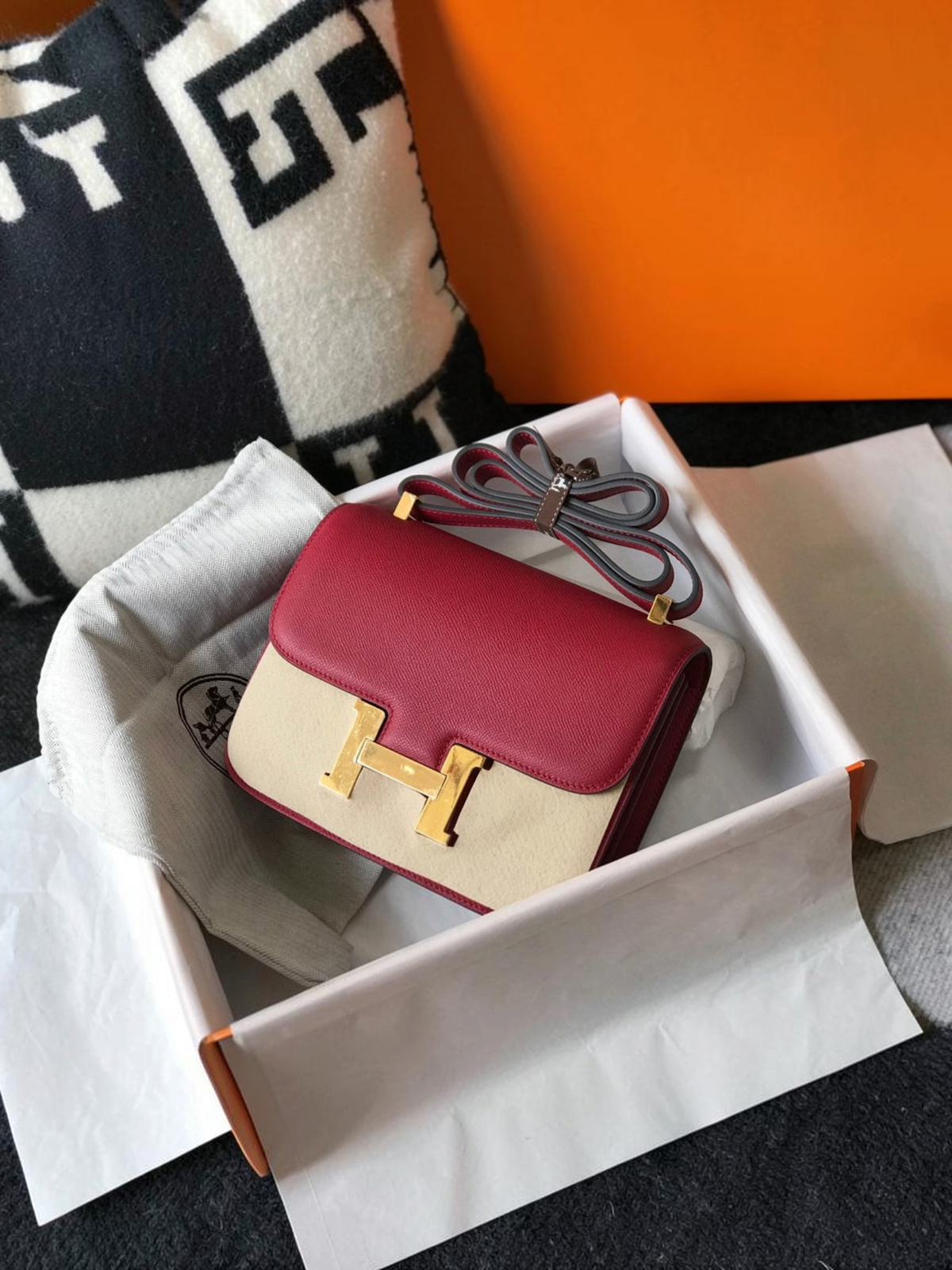 SWORD LUXURY marka, altın H tokalı, bordo ve bej renkli deri Hermès Constance 18 çanta kutusunda.