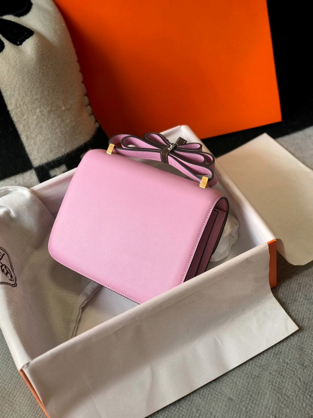 SWORD LUXURY marka, kutusu içinde sunulan, altın tonlu H tokalı, açık pembe deri Hermès Constance 18 çanta.