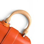 SWORD LUXURY Saïgon PM handbag featuring a smooth orange leather body and a natural beechwood top handle.
