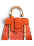 SWORD LUXURY orange Goyardine canvas Saïgon PM handbag with beechwood handle and leather trim in front of Goyard box