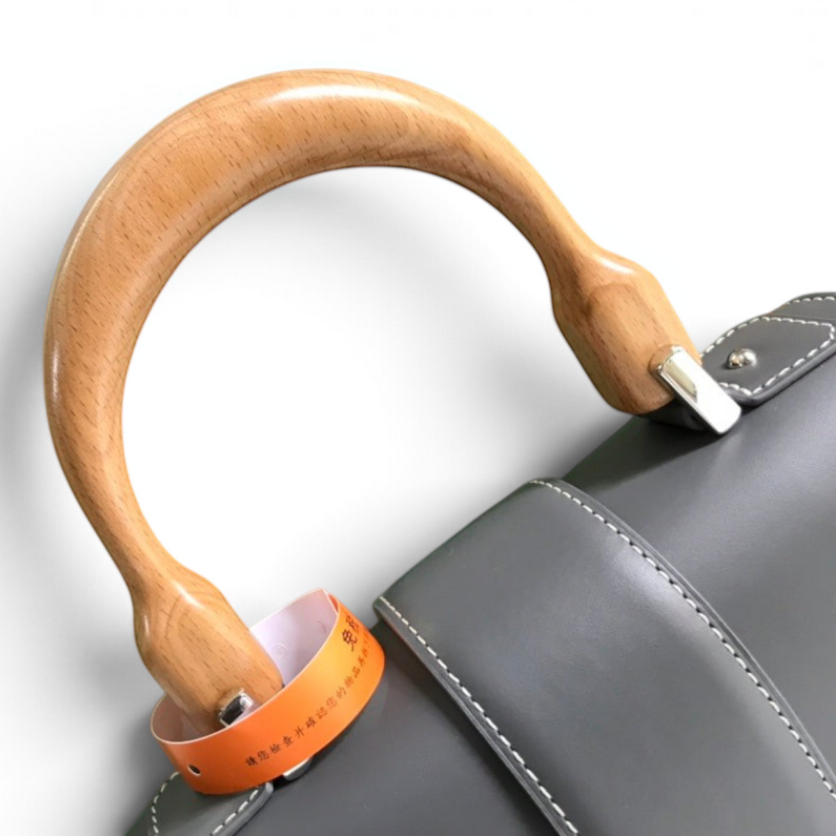 SWORD LUXURY Saïgon PM handbag featuring a smooth grey leather flap and a distinctive curved beechwood top handle.