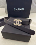 Black belt with Chanel logo on a black box, with Chanel branding in the background.