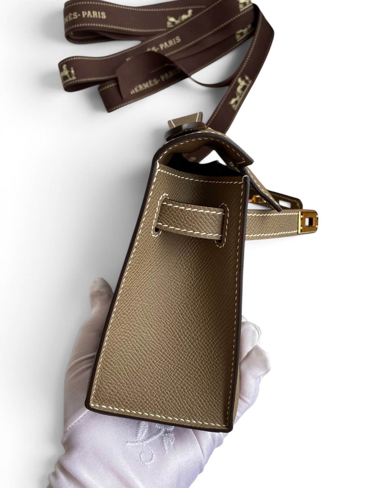 SWORD LUXURY 22 cm Mini Kelly çanta, kahverengi Epsom deri dokusu ve yan detayları ile kutusunda sergileniyor.