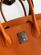 SWORD LUXURY marka turuncu Epsom deri Hermès Birkin 30 çanta, gümüş donanım ve ikonik dikiş detayları ile.