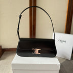 Black handbag with gold clasp on a white box, with a Celine bag in the background.