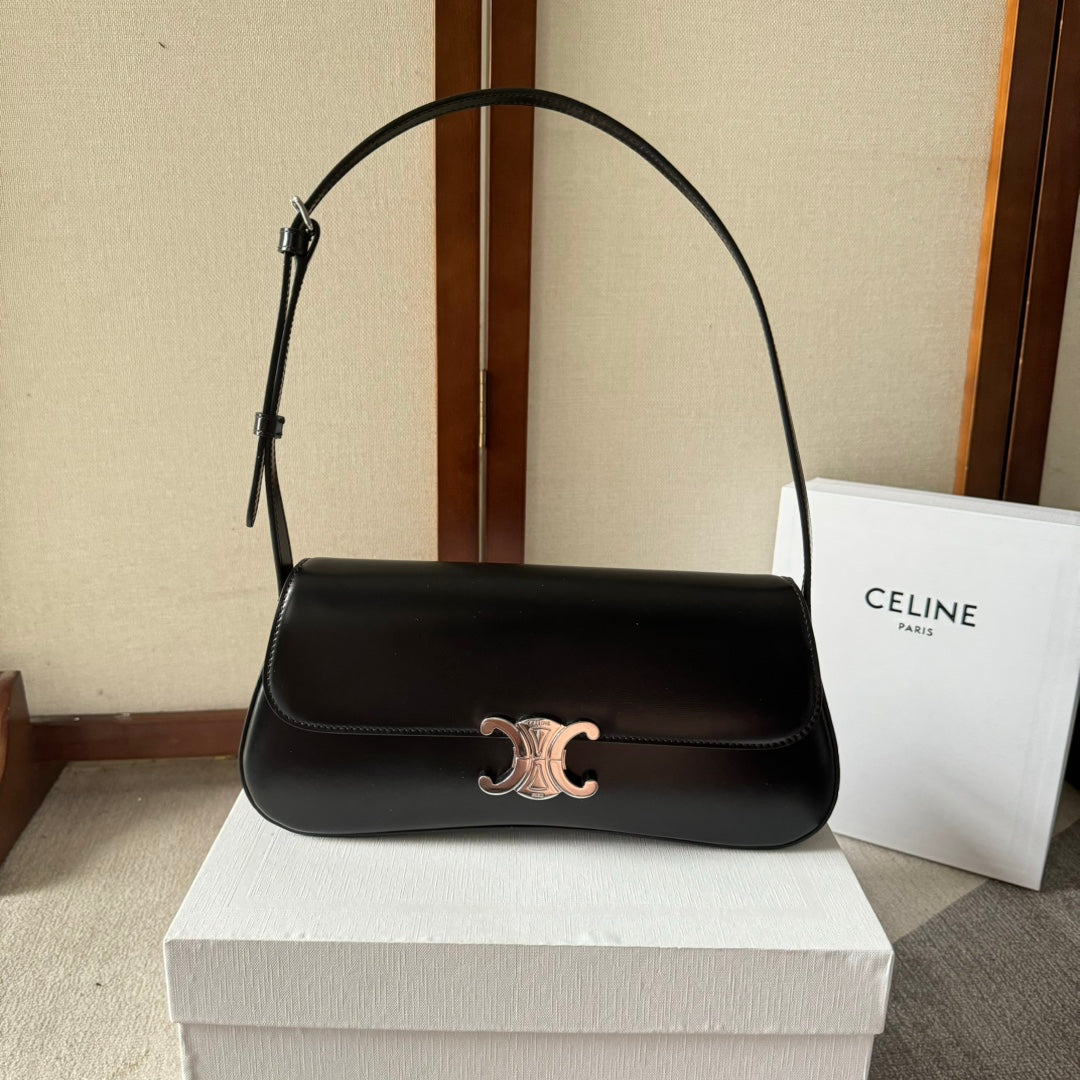Black handbag with gold clasp on a white box, with a Celine bag in the background.