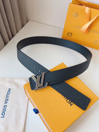 Black belt with silver buckle on a Louis Vuitton box with packaging in the background.