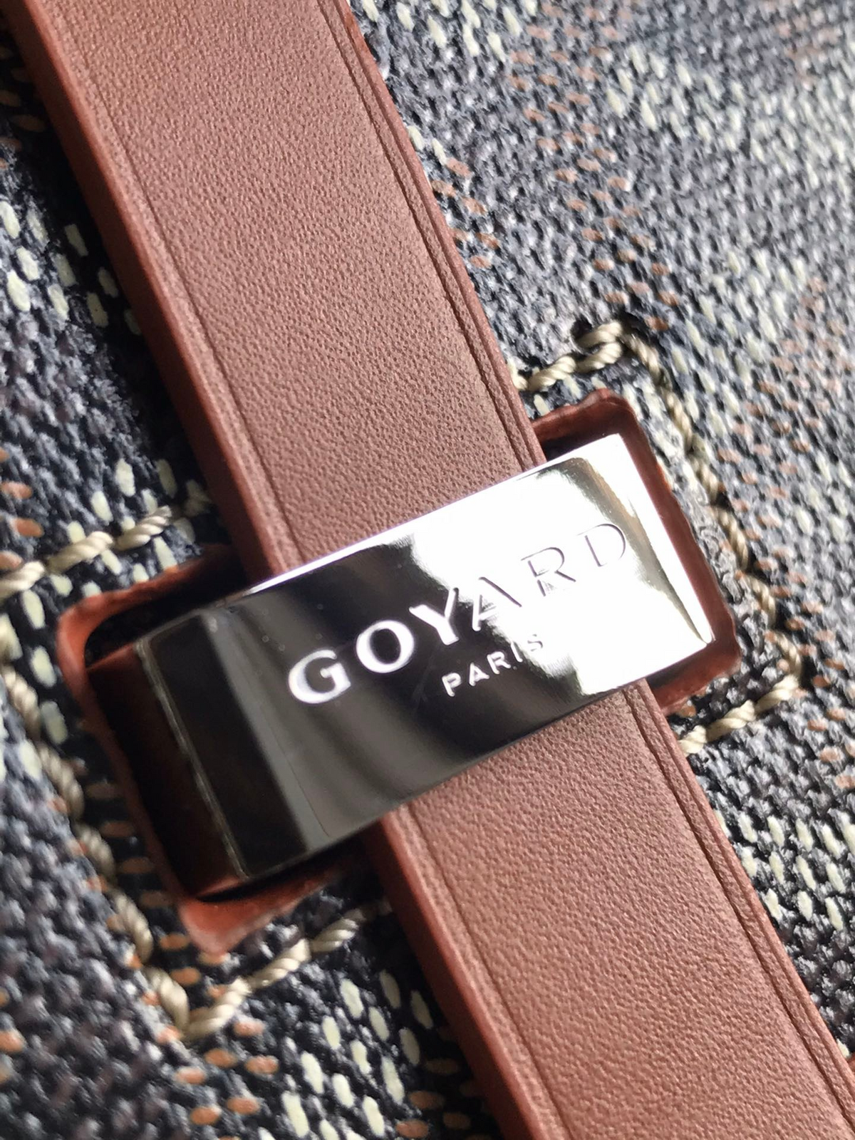 Close-up of SWORD LUXURY Belvédère II messenger bag showing Goyardine canvas, leather strap, and metal logo buckle.