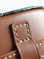 SWORD LUXURY Belvédère II messenger bag showing close-up of brown leather trim with white contrast stitching