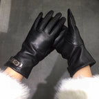 Black leather gloves held up against a dark background