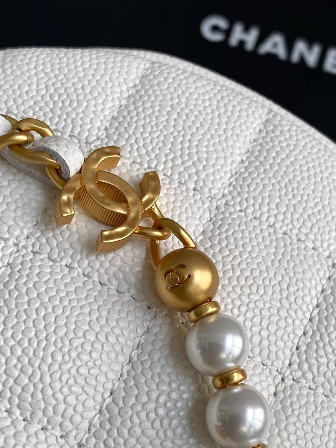 SWORD LUXURY beyaz kapitone deri mini hobo çanta, altın tonlu logo detaylı inci zincir süslemeli yakın çekim.