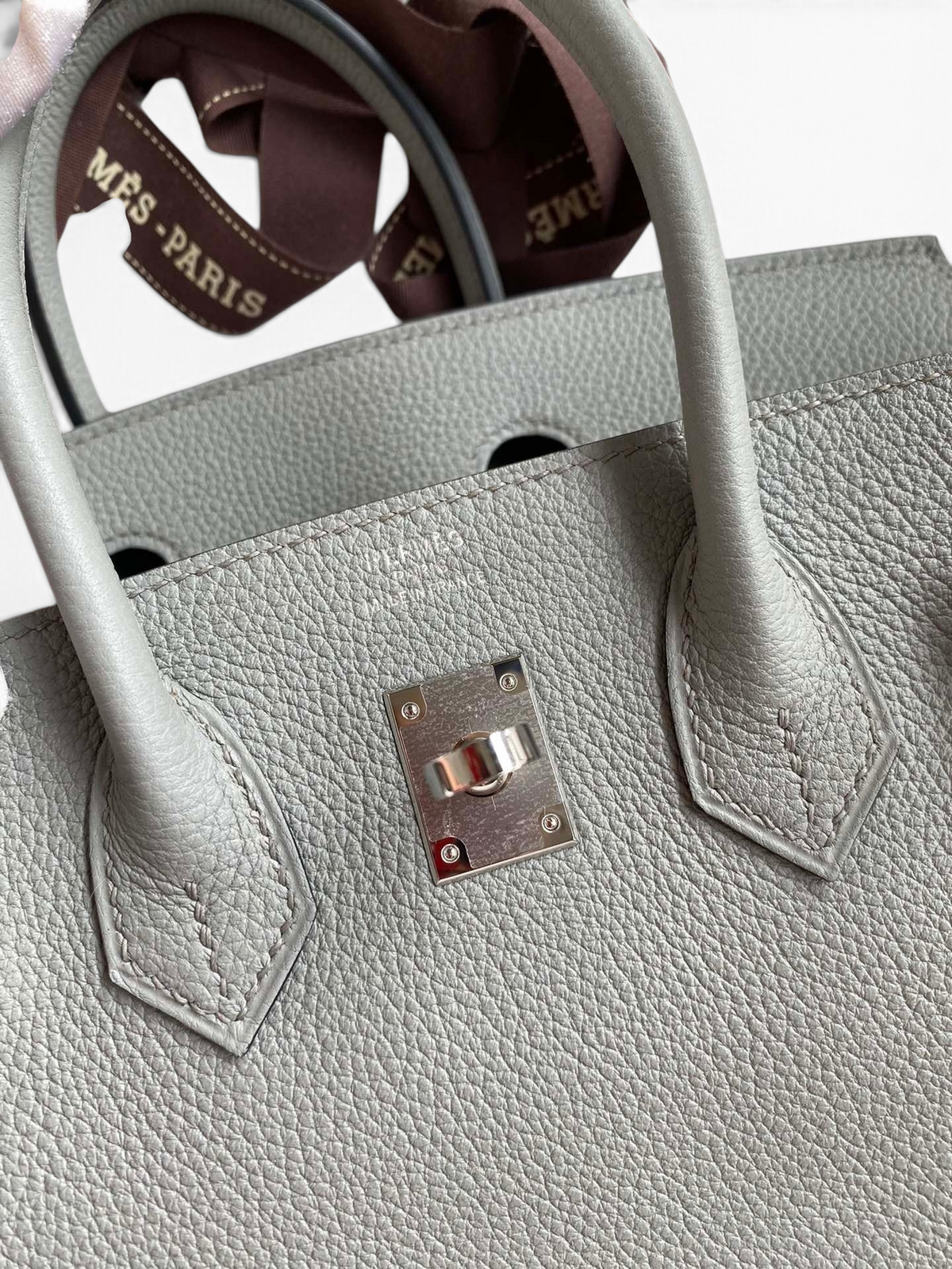 SWORD LUXURY gri renkli, Togo deriden üretilmiş, ikonik kilit detaylı 25 cm Hermès Birkin çanta yakından görünümü.