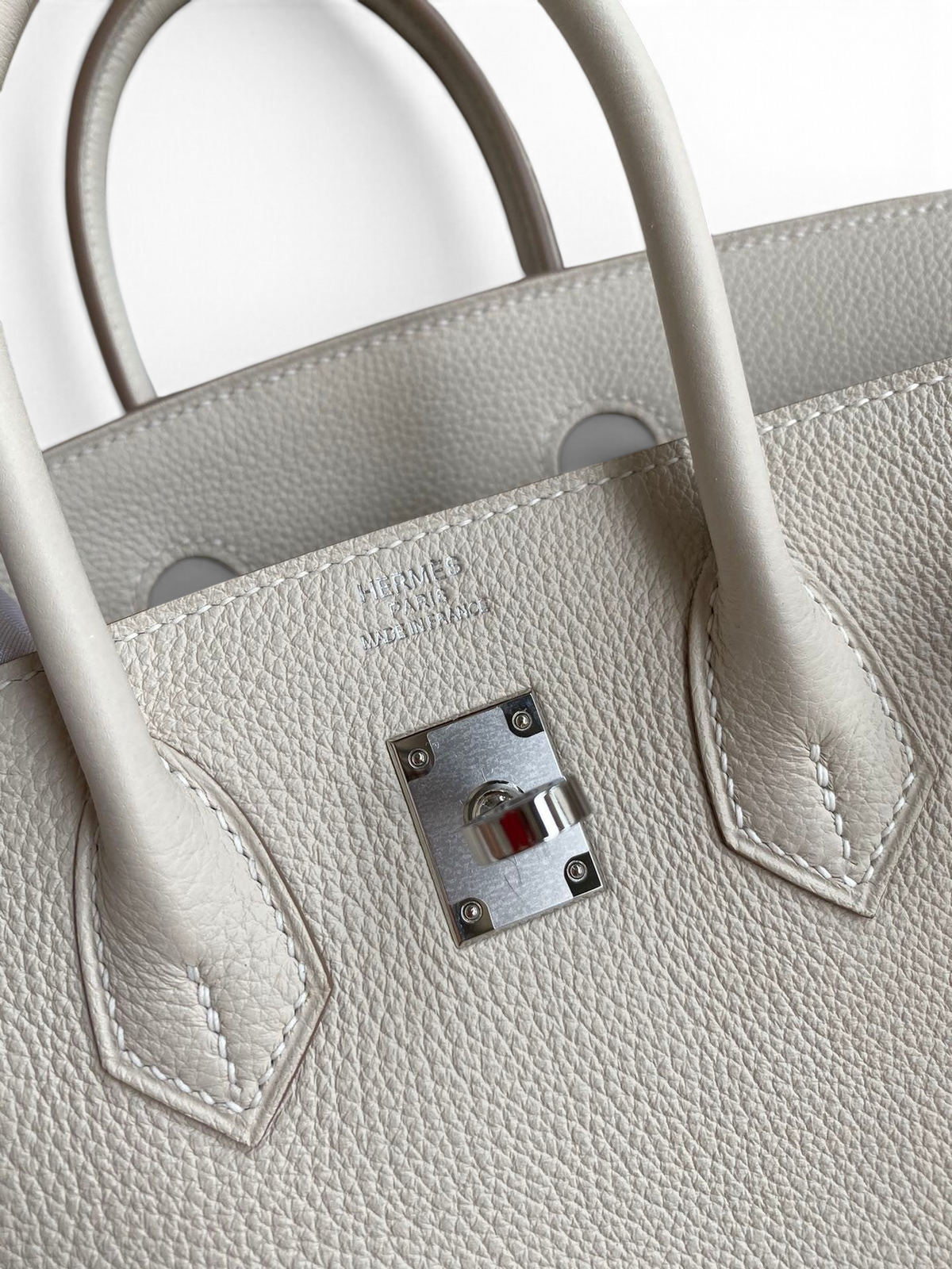 SWORD LUXURY imzalı, beyaz Togo deri Hermès Birkin 25cm çanta, gümüş donanım ve ikonik kilit detayı ile.