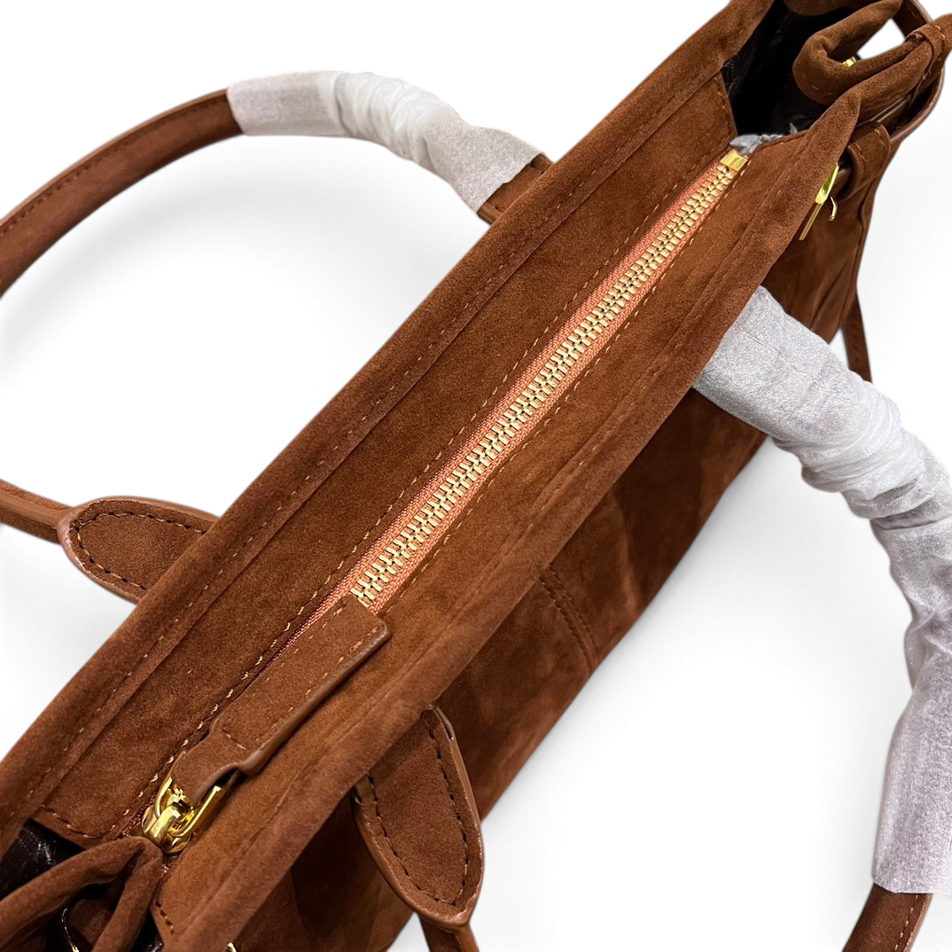 SWORD LUXURY kahverengi süet çanta, altın rengi fermuar detaylı ve koruyucu ambalajlı saplara sahip üstten görünüm.