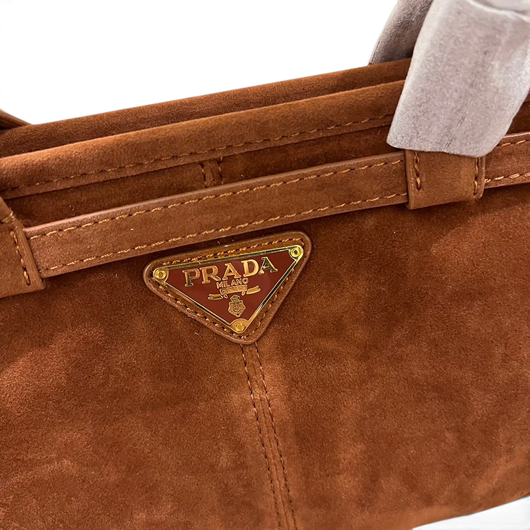 SWORD LUXURY taba rengi süet çanta, üzerinde altın tonlu metal logo detayı ve zarif dikişler bulunuyor.