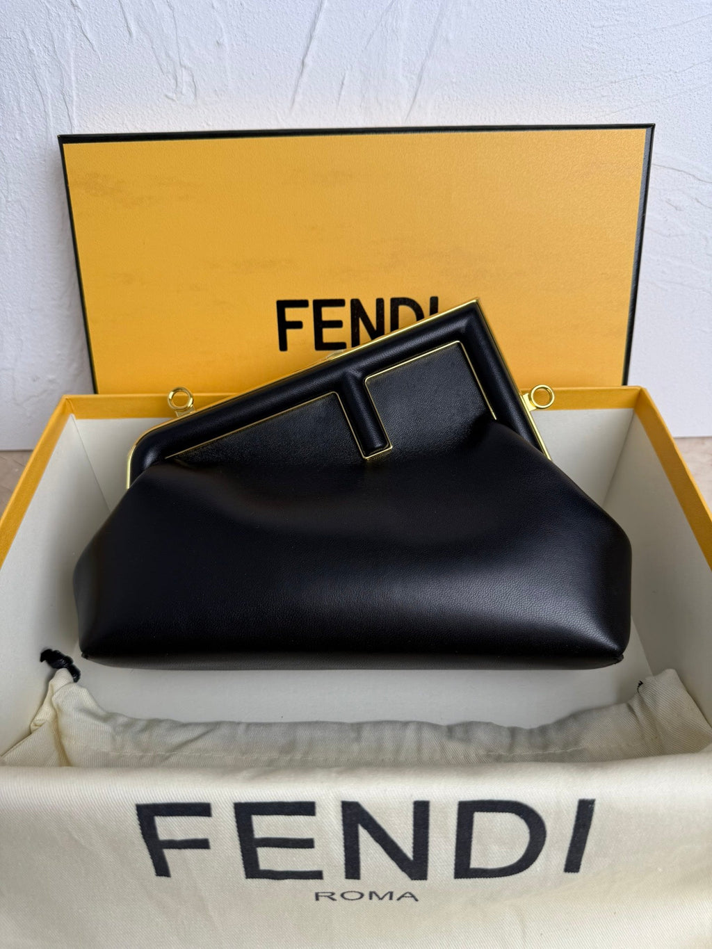 Black Fendi handbag in an open Fendi box on a white background