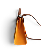 SWORD LUXURY Hermès Herbag 31 turuncu kanvas ve kahverengi deri detaylı çanta, yandan görünüm.