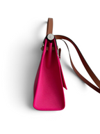 SWORD LUXURY marka, canlı pembe kanvas ve kahverengi deri detaylı, yan profilden görünen Hermès Herbag 31 çanta.