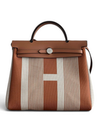 SWORD LUXURY Hermès Herbag 31 çanta, kahverengi ve beyaz çizgili kanvas gövde, deri kapak ve Clou de Selle detaylı.