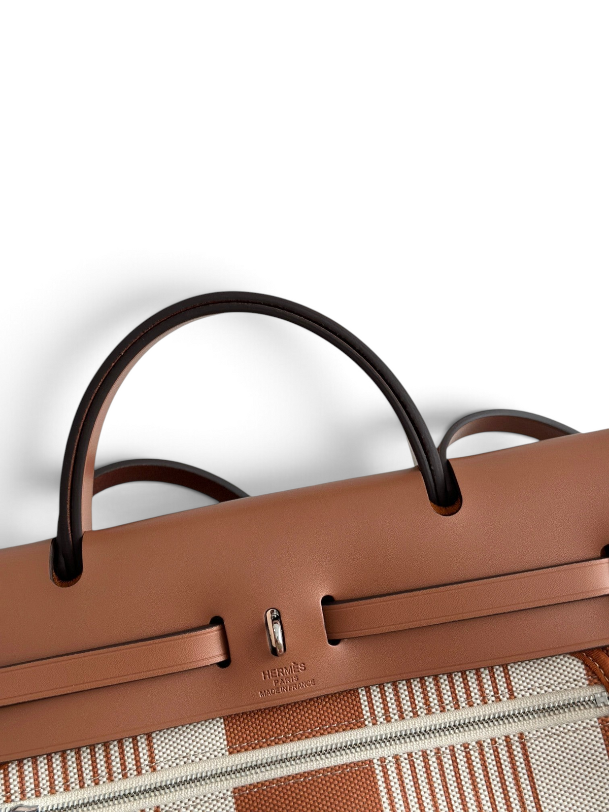 SWORD LUXURY Hermès Herbag 31 çanta, kahverengi deri detaylı ve çizgili kanvas gövdeli, ikonik Clou de Selle kilitli.