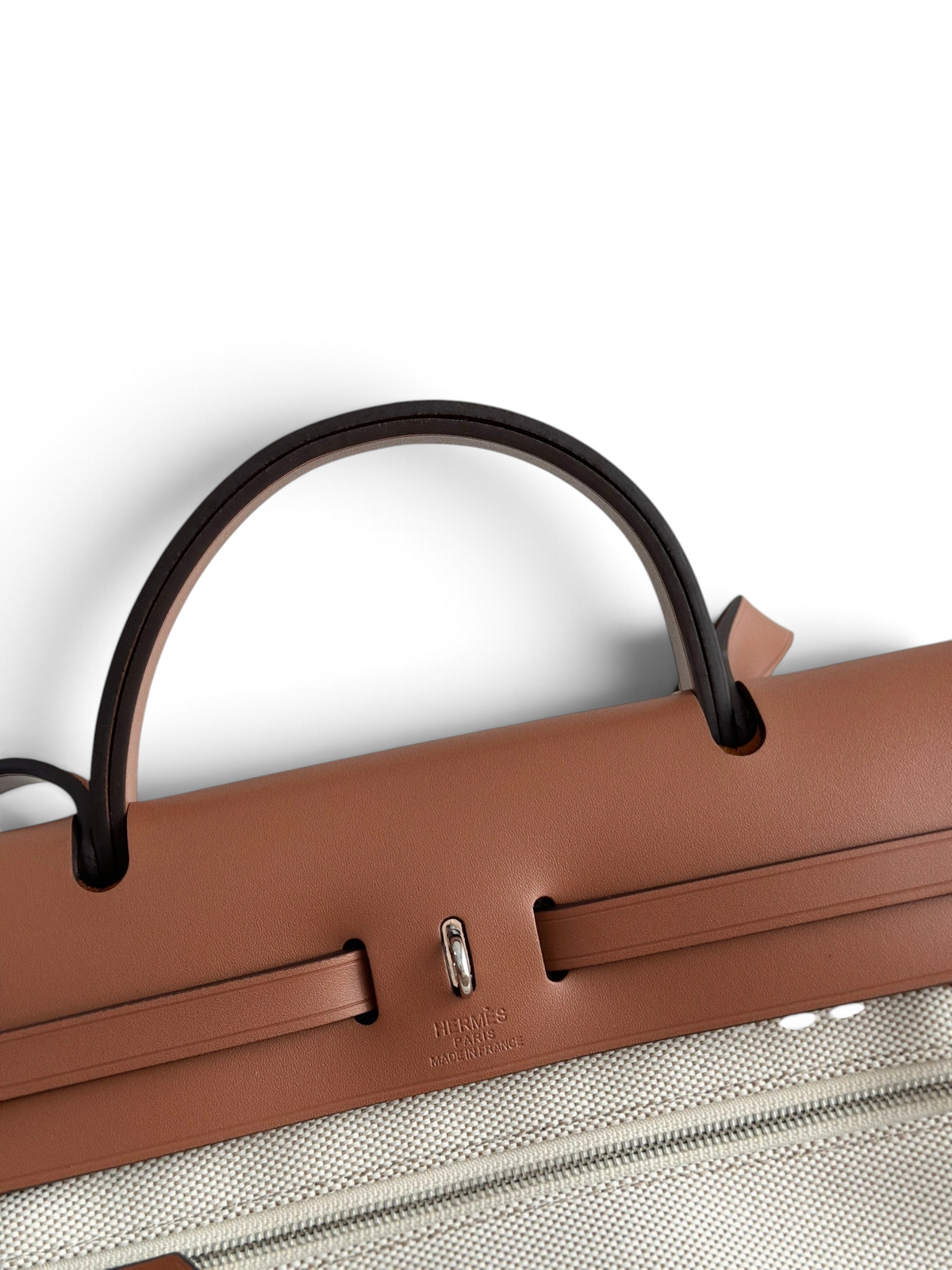 SWORD LUXURY Hermès Herbag 31 çanta, taba rengi deri kapaklı ve bej kanvas gövdeli, ikonik Clou de Selle kilit detaylı.
