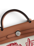 SWORD LUXURY Hermès Herbag 31 çanta, kahverengi deri kapaklı, Clou de Selle kilit detaylı ve sanatsal baskılı kanvas gövdeli.