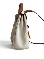 SWORD LUXURY Hermès Herbag 31 çanta, kahverengi deri detaylı ve sanatsal baskılı bej kanvas gövde, yan profil görünümü