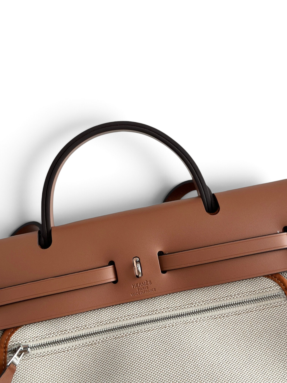 SWORD LUXURY Hermès Herbag 31 çanta, taba rengi deri kapaklı ve bej kanvas gövdeli, şık Clou de Selle detaylı.