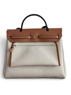 SWORD LUXURY Hermès Herbag 31, bej kanvas ve taba deri detaylı, Clou de Selle kilitli şık el ve omuz çantası.